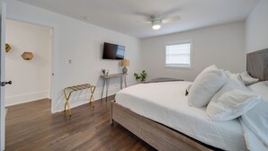 Een slaapkamer met een bed, een plafondventilator, een televisie, een raam en een deur.