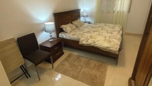 Een slaapkamer met een bed, een bureau, een stoel en een nachtkastje.