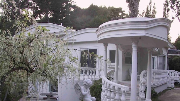 A white gazebo with columns and a statue of a seated figure.
