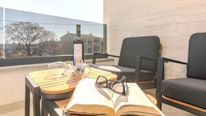 En balkon med et bord, en vinflaske, glas og en åben bog.