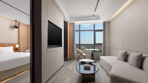 A modern hotel room with a bed, sofa, TV, and a table. - Microtel BY Wyndham Maoming Dianbai (Maoming)