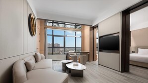 A modern hotel room with a large bed, a sofa, a TV, and a city view. - Microtel BY Wyndham Maoming Dianbai (Maoming)
