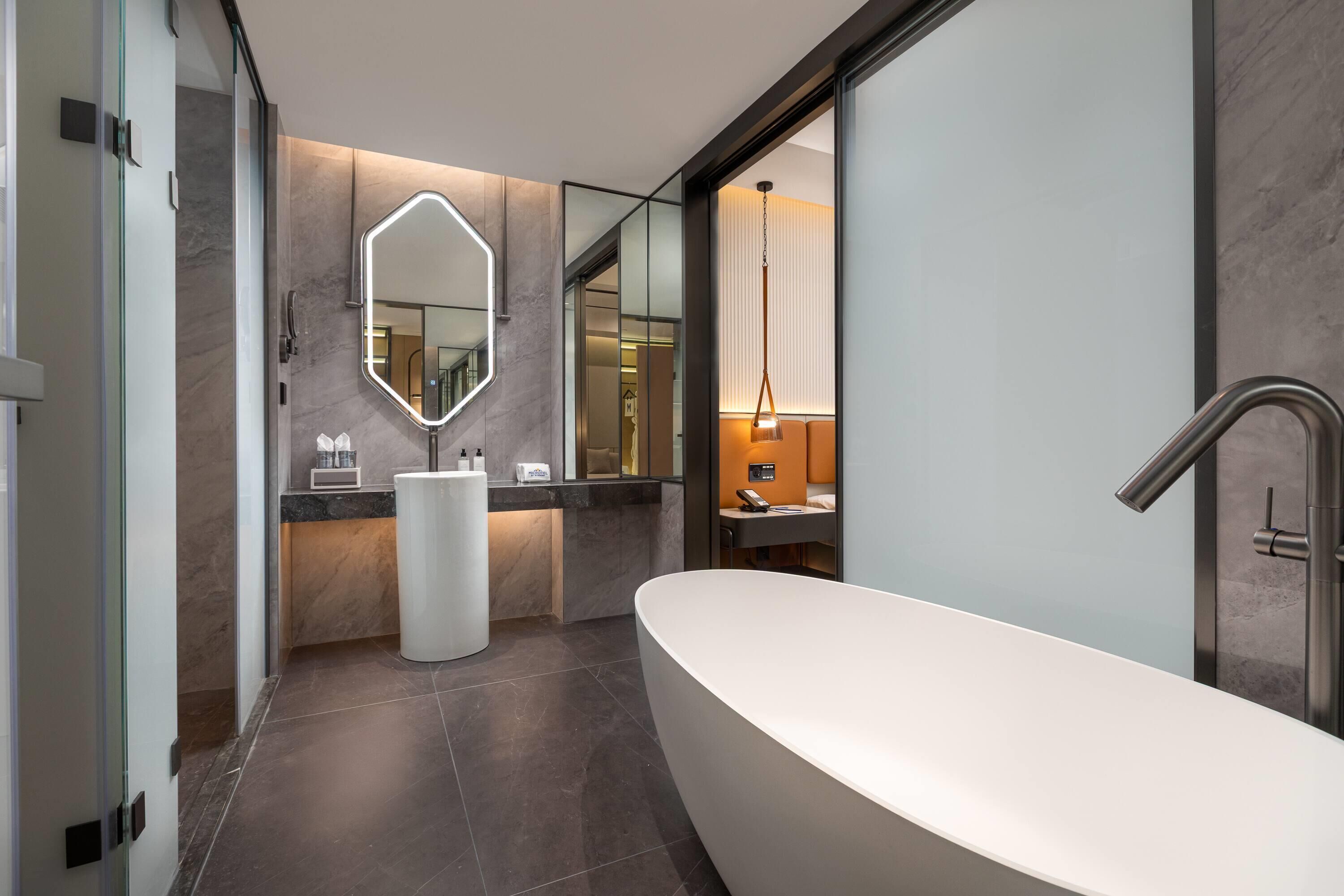 Un baño moderno con una bañera independiente, un espejo grande y un tocador con encimera.