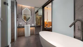Un baño moderno con una bañera independiente, un espejo grande y un tocador con encimera.