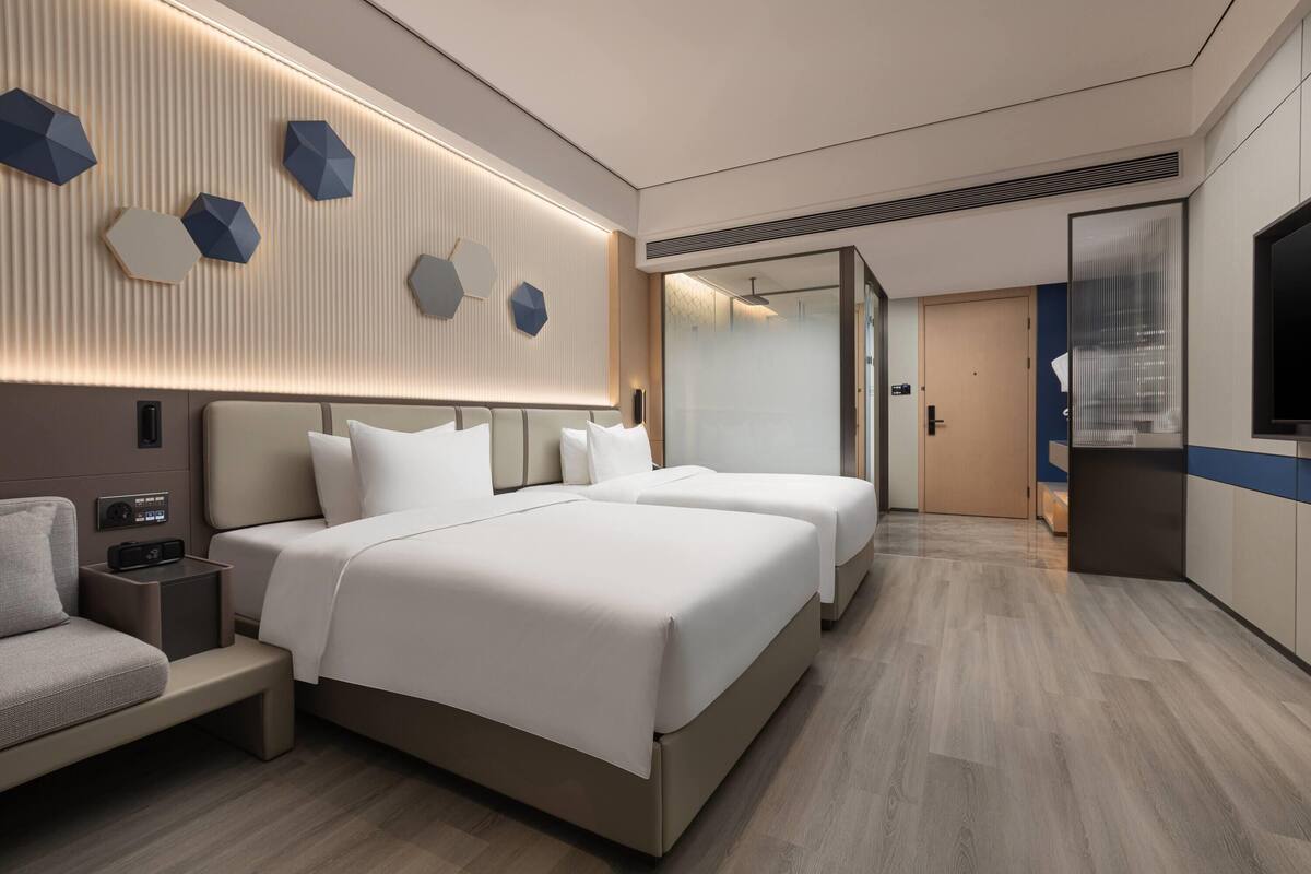 Et moderne hotelværelse med en stor seng, sengeborde, et fjernsyn og en vægmonteret lampe.