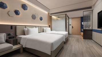 A modern hotel room with a large bed, bedside tables, a TV, and a wall-mounted light fixture.