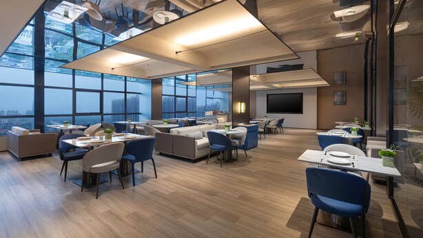 A modern dining area with high ceilings, large windows, and contemporary furniture. - Microtel BY Wyndham Maoming Dianbai (Maoming)