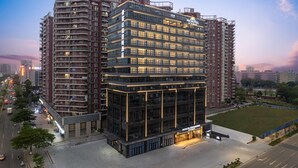 A modern hotel building with multiple floors, large windows, and a well-lit entrance. - Microtel BY Wyndham Maoming Dianbai (Maoming)