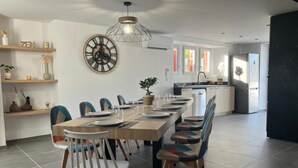 Un espace repas moderne avec une table en bois, des chaises et une grande horloge murale.