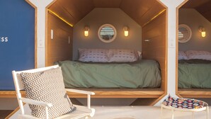 Una habitación compacta de forma hexagonal con una cama, una silla y una mesita.