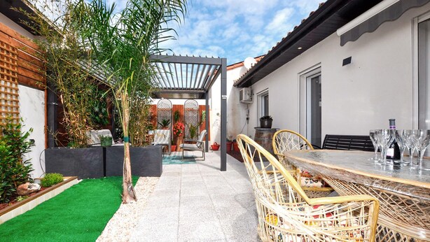 Eine Terrasse mit Esstisch, Stühlen und einer Pergola.