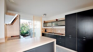 Eine moderne Küche mit dunklen Schränken, einer Holz Arbeitsplatte und einem sichtbaren Außenbereich mit Baum und Bank.