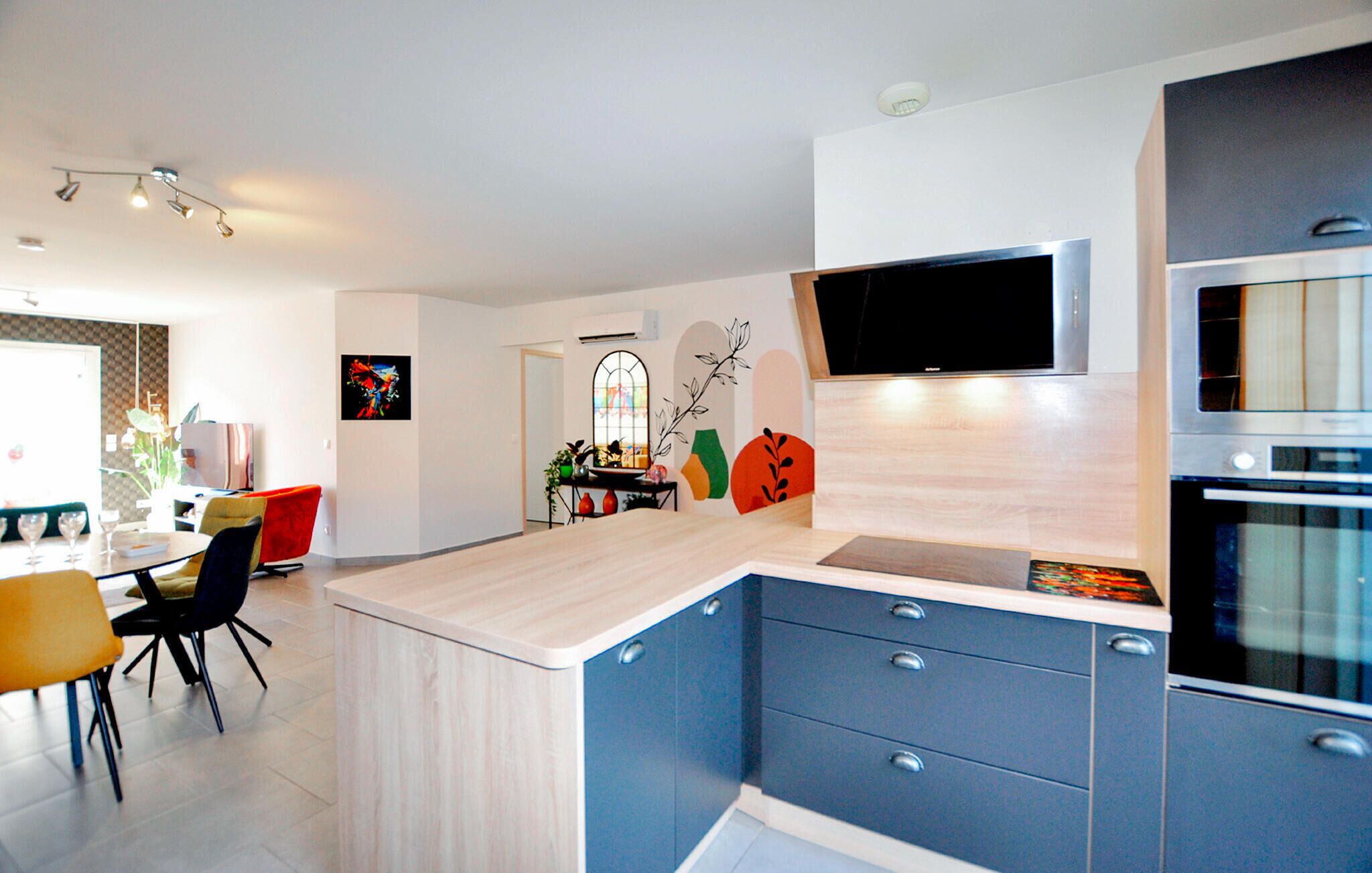 A modern kitchen with a wooden island, blue cabinets, and a built-in oven.