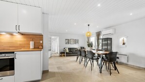 Una cocina moderna con armarios blancos, encimera de madera y horno empotrado.