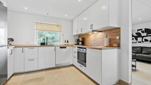 Una cocina moderna con armarios blancos, una encimera de madera y un horno empotrado.