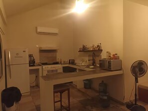 Une cuisine compacte équipée d’un réfrigérateur, d’une cuisinière, d’un four à micro-ondes et d’un ventilateur.