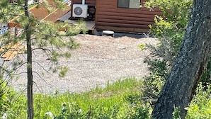 Una cabaña con techo inclinado, una chimenea y un ventanal pequeño.