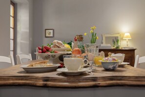 Une table à manger avec des aliments pour le petit-déjeuner, une carafe et un vase rempli de fleurs.