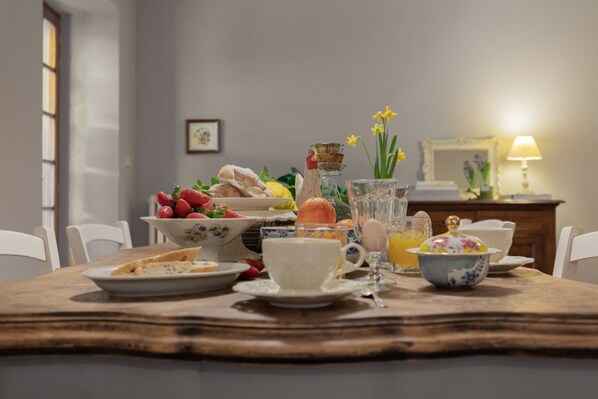 A dining table with breakfast items, a pitcher, and a vase with flowers.