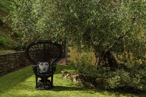 A garden with a bench, a stone wall, and a building in the background. - Villa Essiccatoio by MMega (Lisciano Niccone)