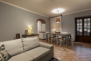 Un salon comprenant un canapé, une table à manger, des chaises, une lampe et une porte avec une fenêtre.