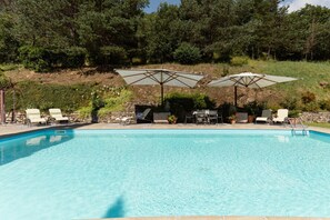 Una piscina con sillones de descanso y sombrillas.