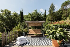Une terrasse avec une balançoire, un tapis à motifs et une plante en pot.