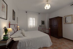 A bedroom with a bed, a wooden wardrobe, a radiator, and a window with curtains.