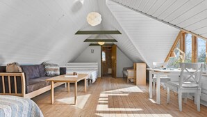 A cozy attic bedroom with a wooden floor, a bed, a sofa, and a desk with a chair. - Nice home in Farsø with WiFi (Farsø)