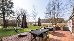 A wooden deck with outdoor furniture, including a table and chairs, and a swing set. - Nice home in Farsø with WiFi (Farsø)