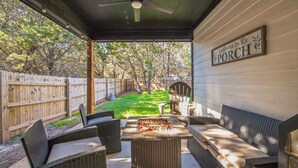 Eine überdachte Terrasse mit Korbmöbeln, einem Grill und einem Schild mit der Aufschrift 'Welcome to the Porch'.