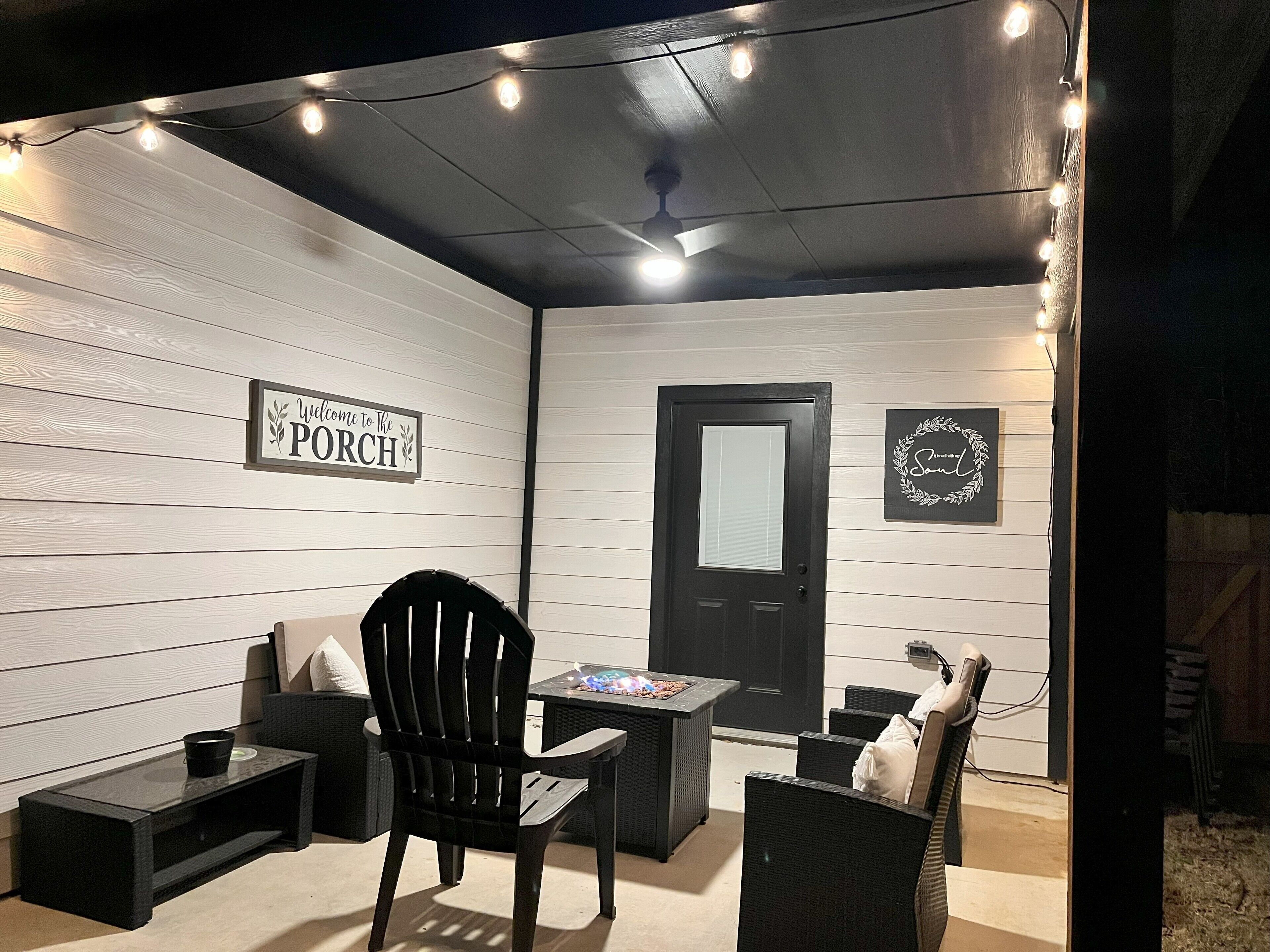 A cozy porch area with a black chair, a small table, and a decorative sign that reads "Welcome to The Porch".