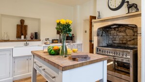 A kitchen with a stone oven, a wooden countertop, and a vase with flowers.