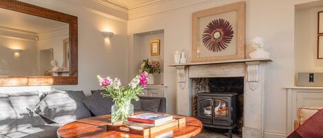 A living room with a fireplace, a round wooden coffee table, a sofa, and a mirror.