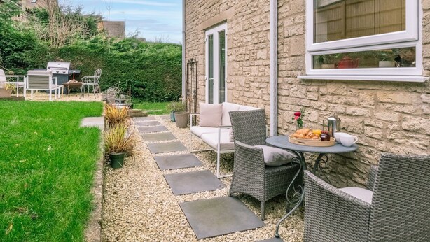 A patio with outdoor furniture, a grill, and a table set with food and drinks.