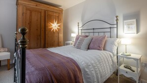 A bedroom with a bed, nightstands, a wooden wardrobe, and a star-shaped light fixture.
