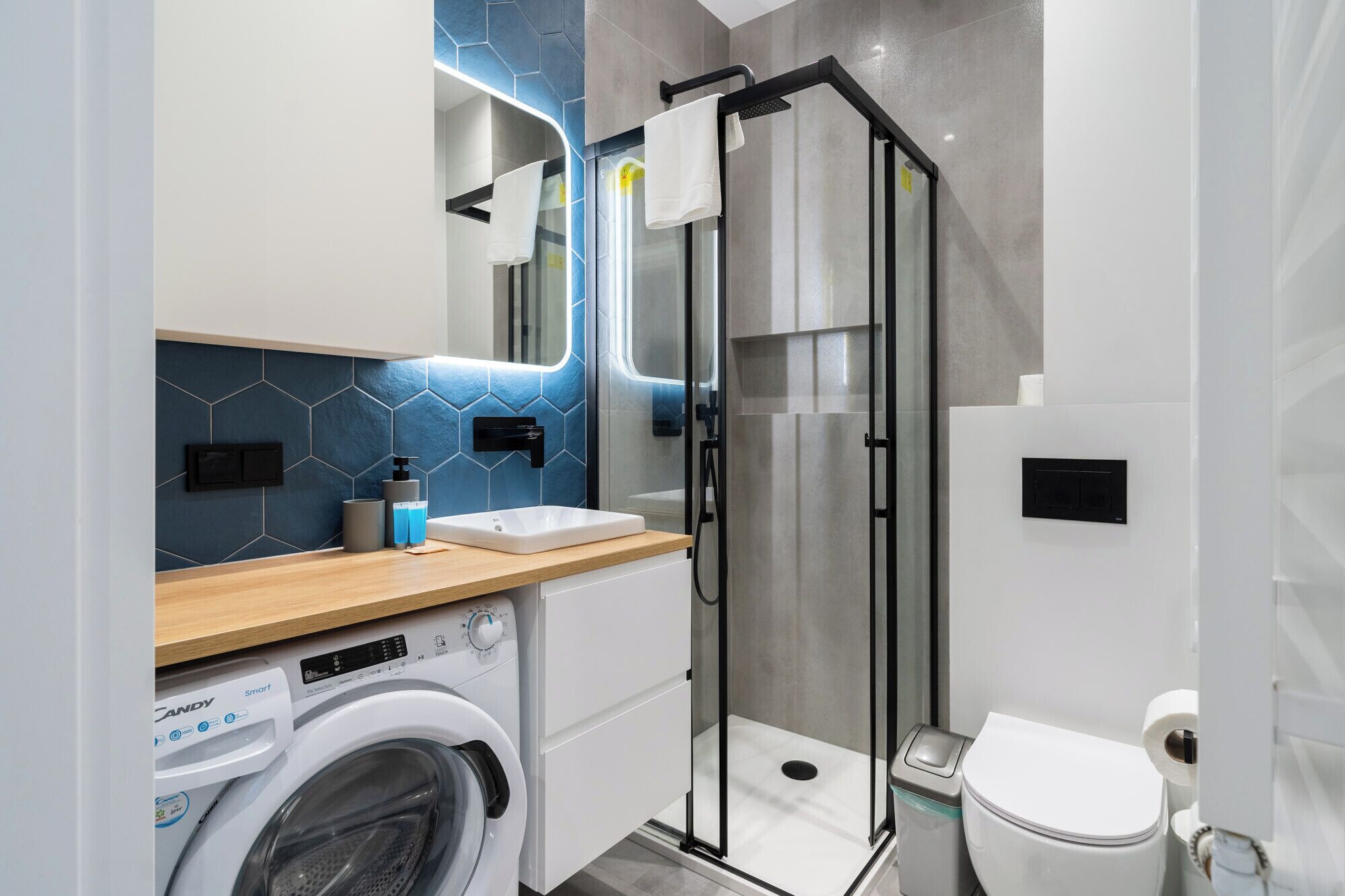 Un bagno moderno con cabina doccia in vetro, lavatrice integrata e un water.