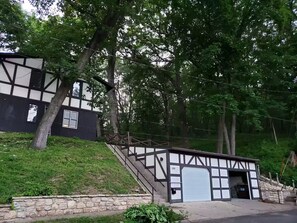 A building with a steep staircase leading to a garage door, surrounded by trees and greenery. - House On the Hill Charming 3-bedroom house with Rec Room, in lovely Savanna (Savanna,)