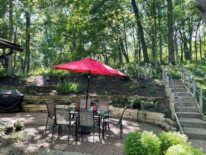 A patio area with a red umbrella, outdoor furniture, and a stone staircase leading up.
