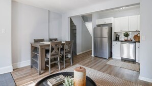 A modern kitchen with stainless steel appliances, a dining area with wooden furniture, and a staircase leading to another level. - 3 Bedroom Beauty in Bloomfield (Bloomfield)
