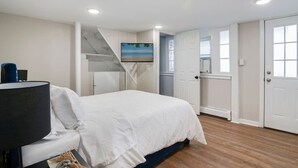 A bedroom with a bed, a TV, a staircase, and a door leading to another room. - 3 Bedroom Beauty in Bloomfield (Bloomfield)