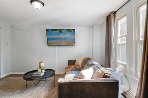A living room with a sofa, a coffee table, and a painting on the wall.