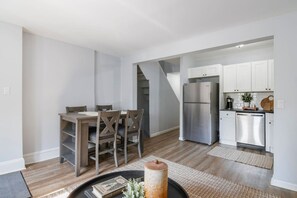 A modern kitchen with stainless steel appliances, a dining area with wooden furniture, and a staircase leading to another level.