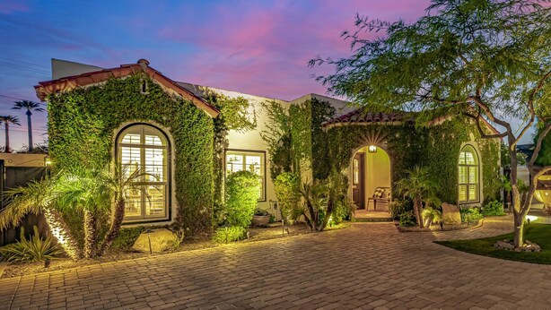 A house with a brick pathway leading to the entrance, surrounded by lush greenery and a well-lit garden. - Cocktails & Cacti | Encanto-Palmcroft Villa | Temp-Controlled Pool + Hot Tub | 4 Suites (Phoenix)