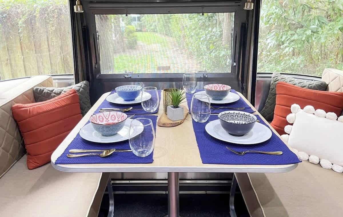 A dining area with a table set for two, featuring patterned bowls, glasses, and cutlery.
