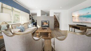 Ein modernes Wohnzimmer mit Kamin, Fernseher und einer Treppe, die in eine weitere Ebene führt.