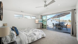 Ein Schlafzimmer mit Bett, Deckenventilator und Balkon mit Tisch und Stühlen.
