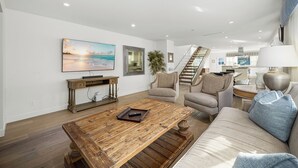 Ein modernes Wohnzimmer mit Couch, Fernseher an der Wand und einem Holztisch.