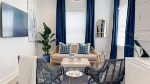 A modern living room with a sofa, two armchairs, a coffee table, a TV, and a large plant. - Modern Duplex 3 Blocks from Forsyth Park (Savannah)