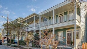 A two-story residential building with a balcony on the upper floor, a front porch, and a garage. - Modern Duplex 3 Blocks from Forsyth Park (Savannah)